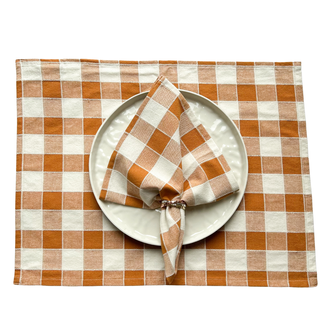 Tischset und Serviette als Set aus Baumwolle. Karomuster in den Farben beige und orange.